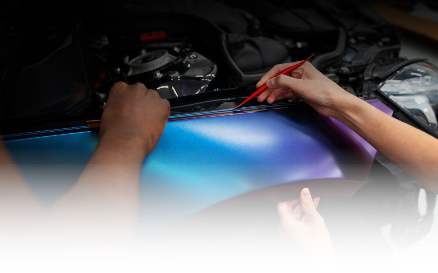 Man using foam cannon to apply thick white foam on a sports car during detailing.