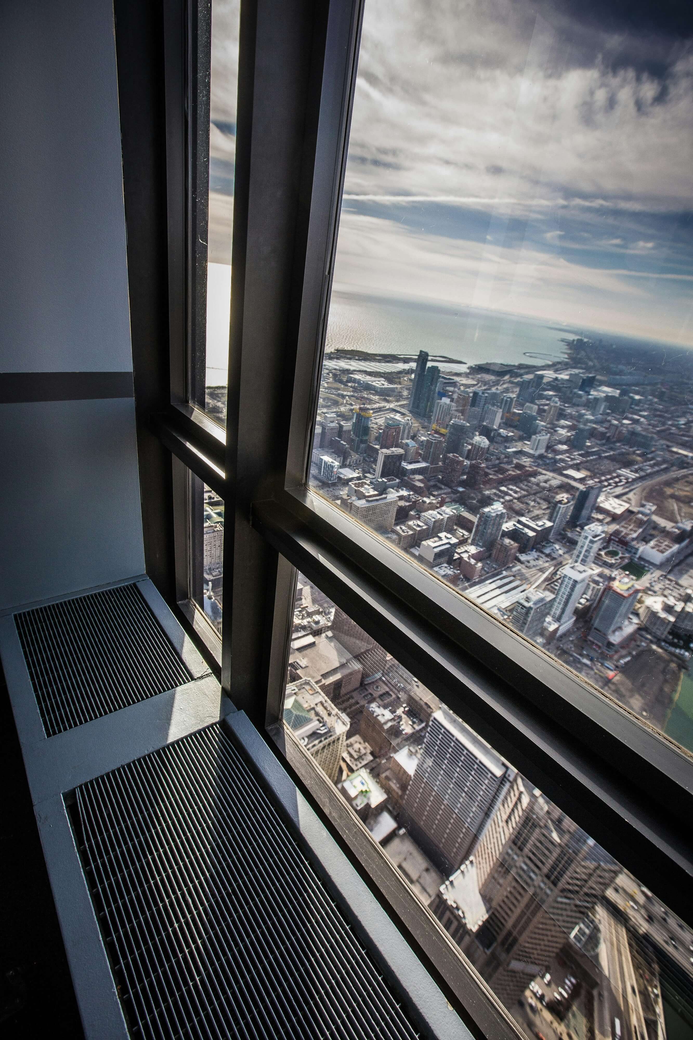 Interior view from a tall building with large floor-to-ceiling windows overlooking a cityscape