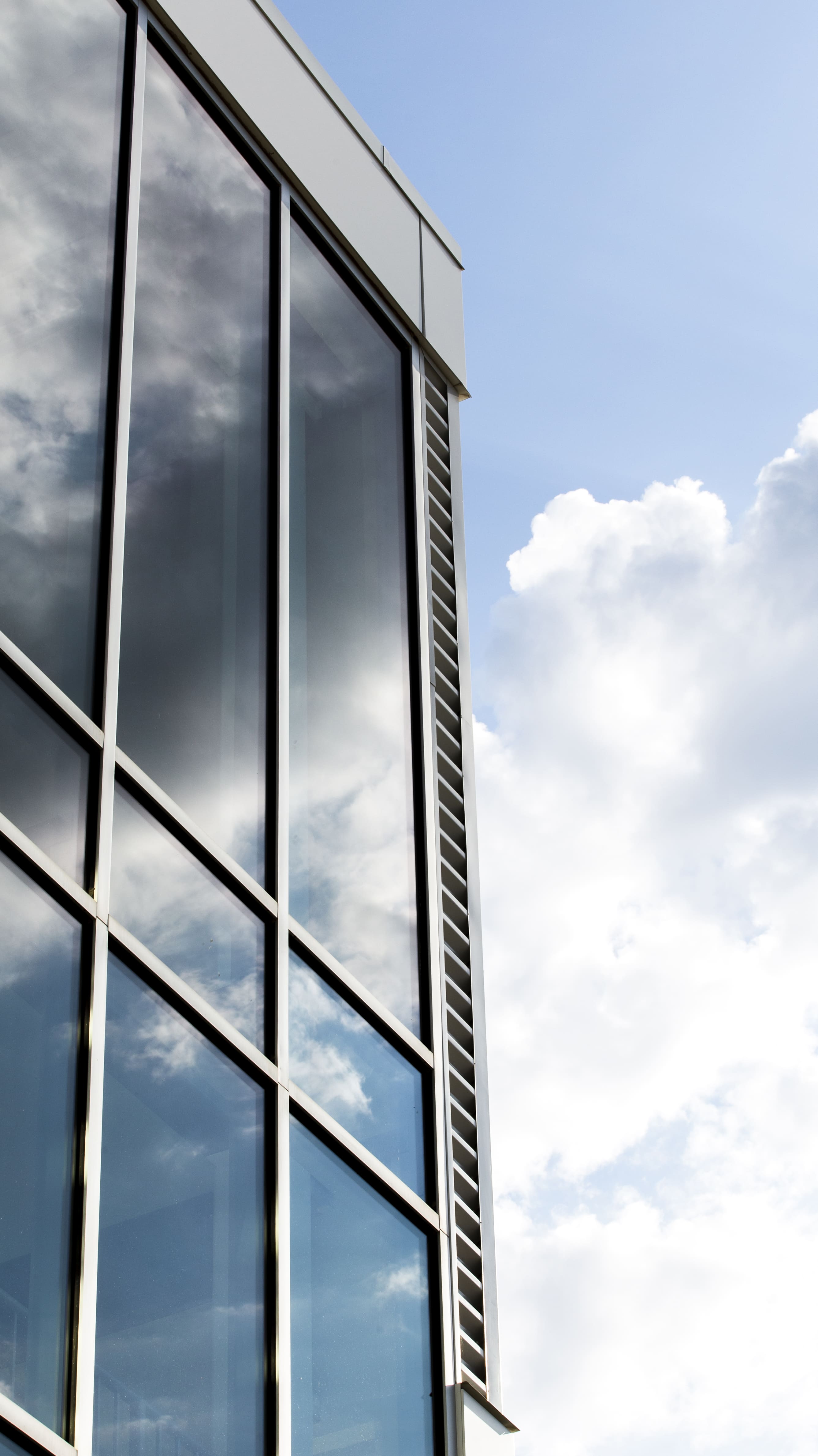 Side view of a modern glass building reflecting the sky