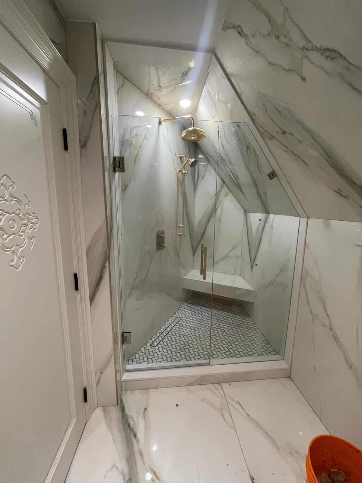Custom glass shower enclosure with black marble tile.