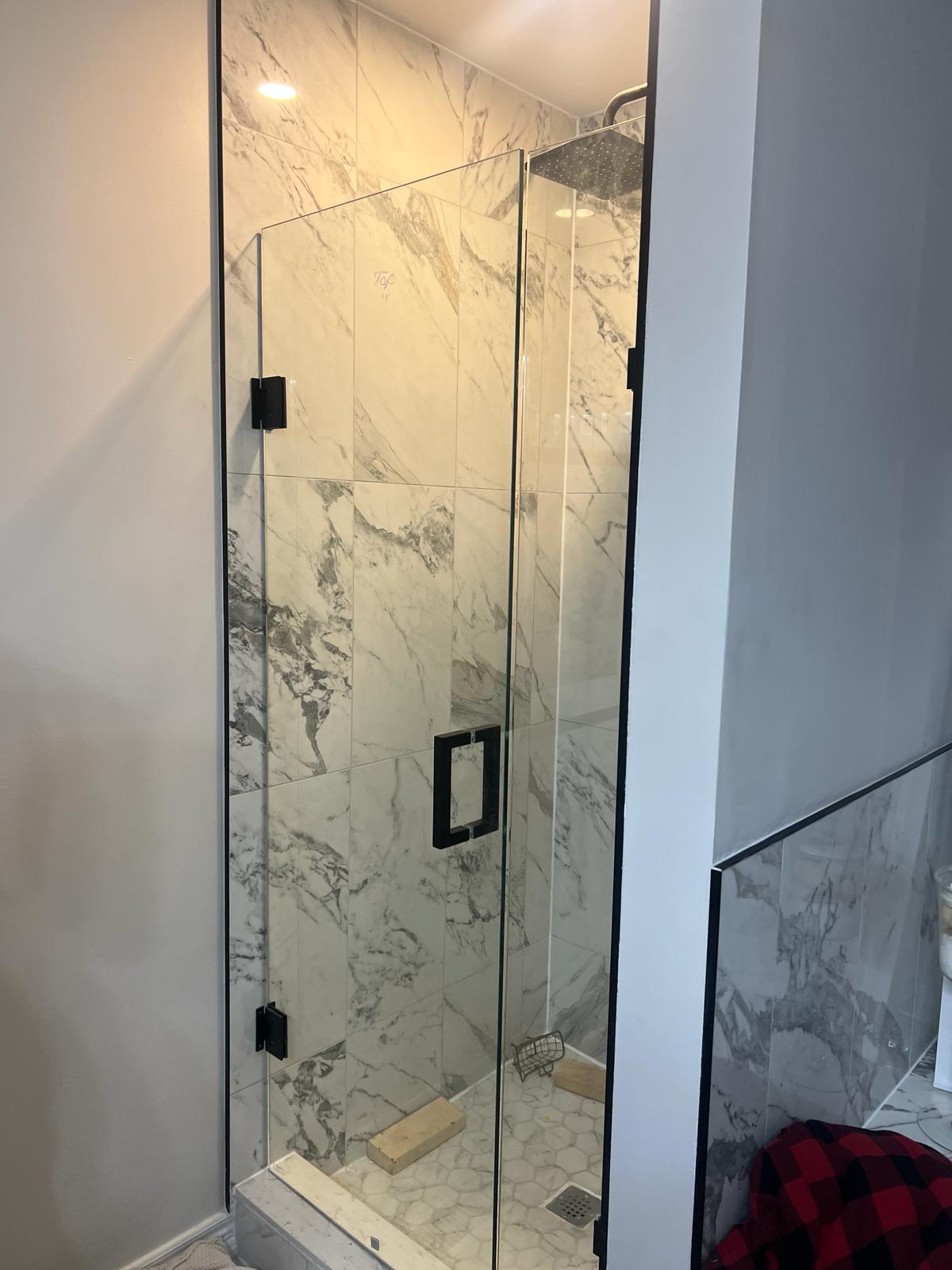 Custom glass shower enclosure with black marble tile.