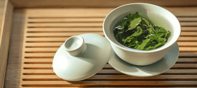 wooden trey with tea leaves in a white cup