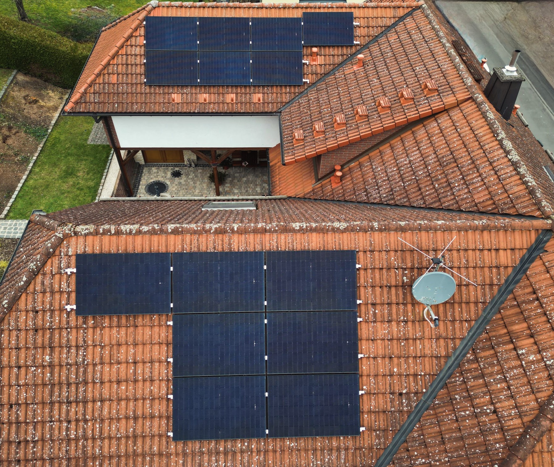 Luftaufnahme eines Hauses mit Solar-Paneelen auf Ziegeldächern und Hof.