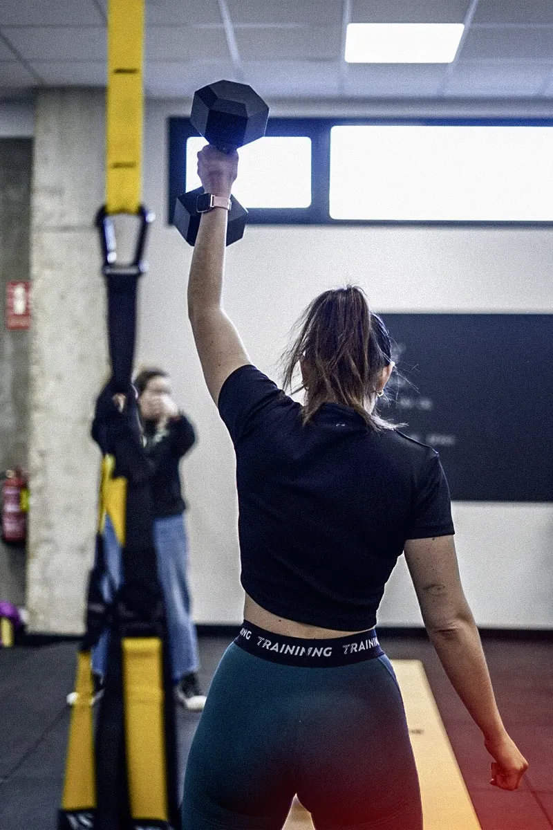 Mujer levantando una pesa con un brazo en 180 training club.