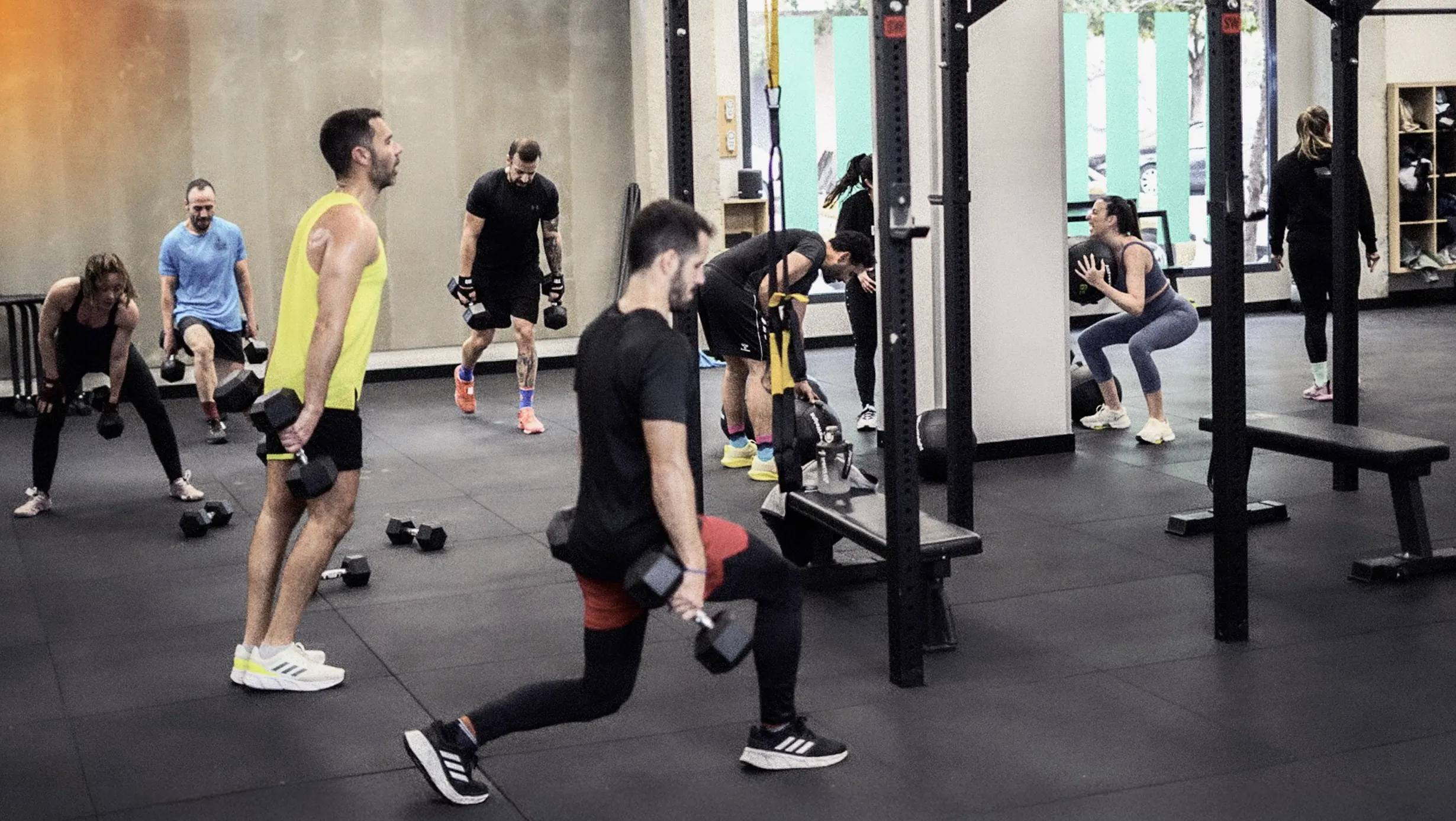 Clase de entrenamiento funcional en 180 training club con varias personas realizando ejercicios con mancuernas y pesas en un espacio amplio y equipado.