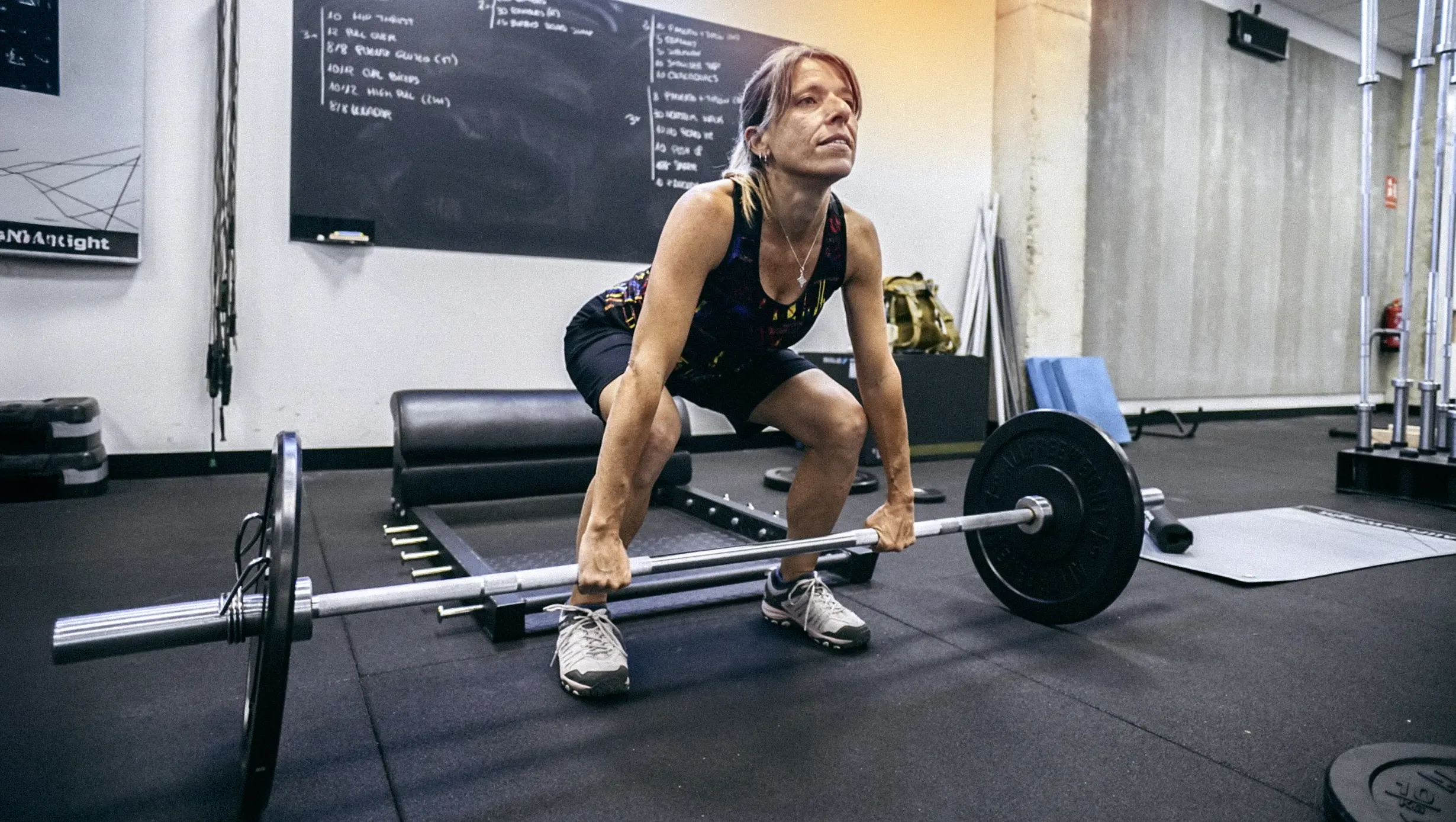 Mujer realizando un ejercicio de peso muerto en 180 training club dentro de una clase de entrenamiento funcional.