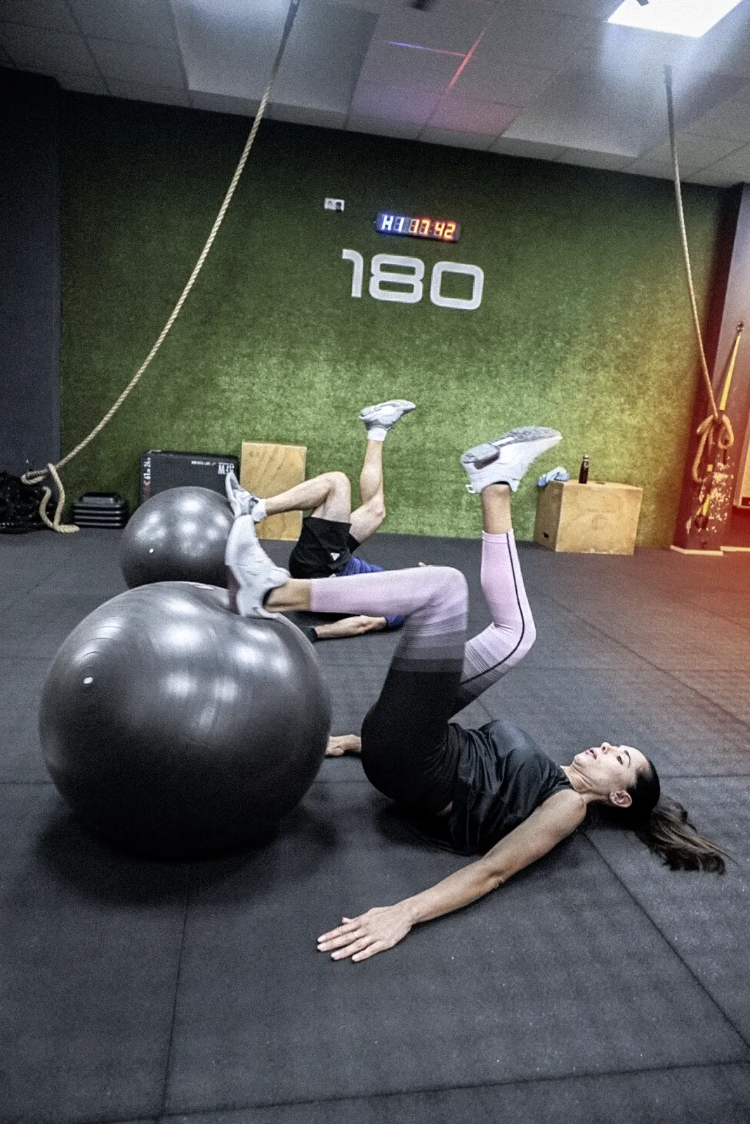 Dos personas haciendo ejercicio en  con balones de estabilidad sobre el suelo en 180 training club.
