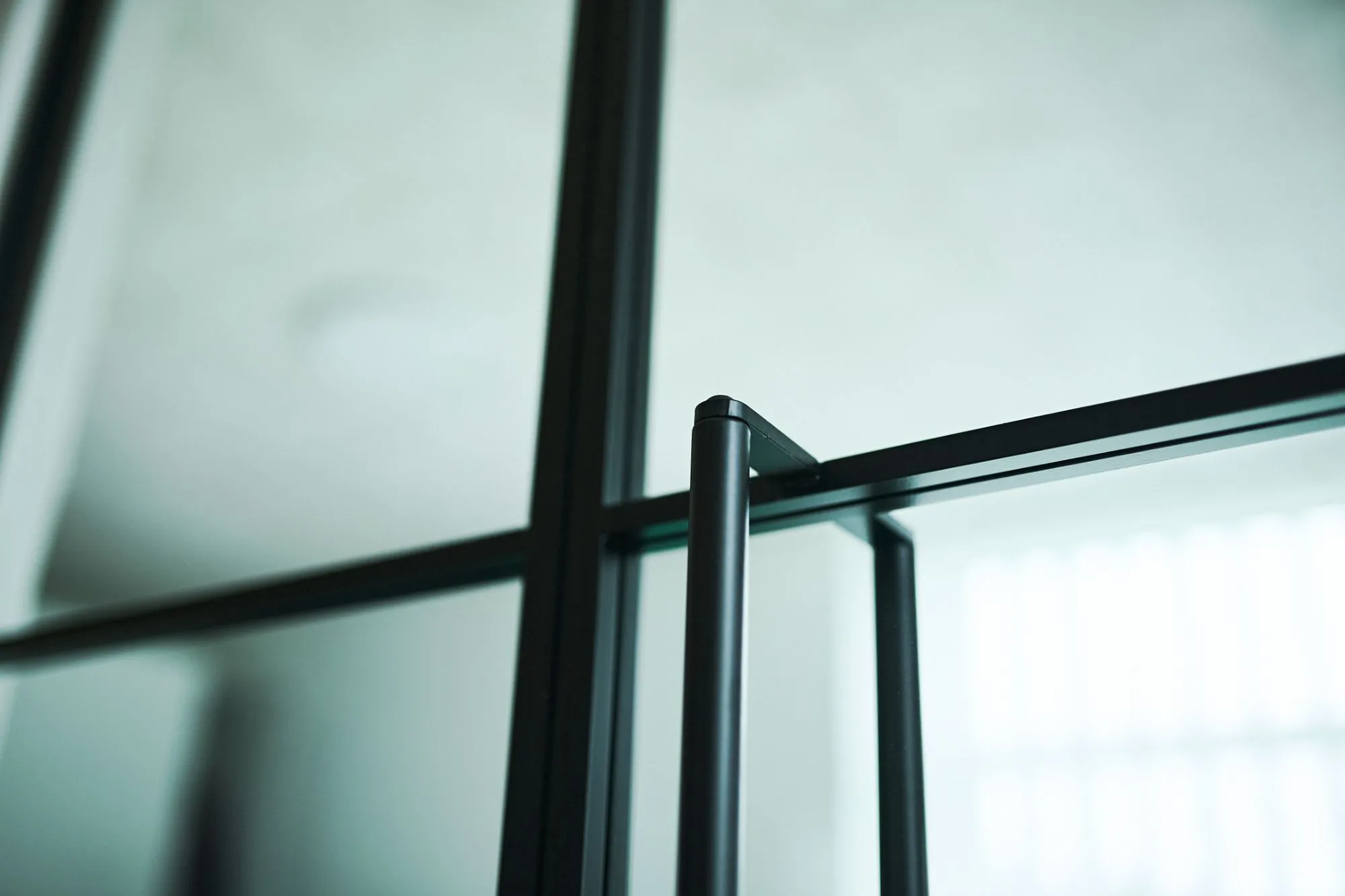 Nærbillede af metalramme og glasvindue med sløret baggrund.