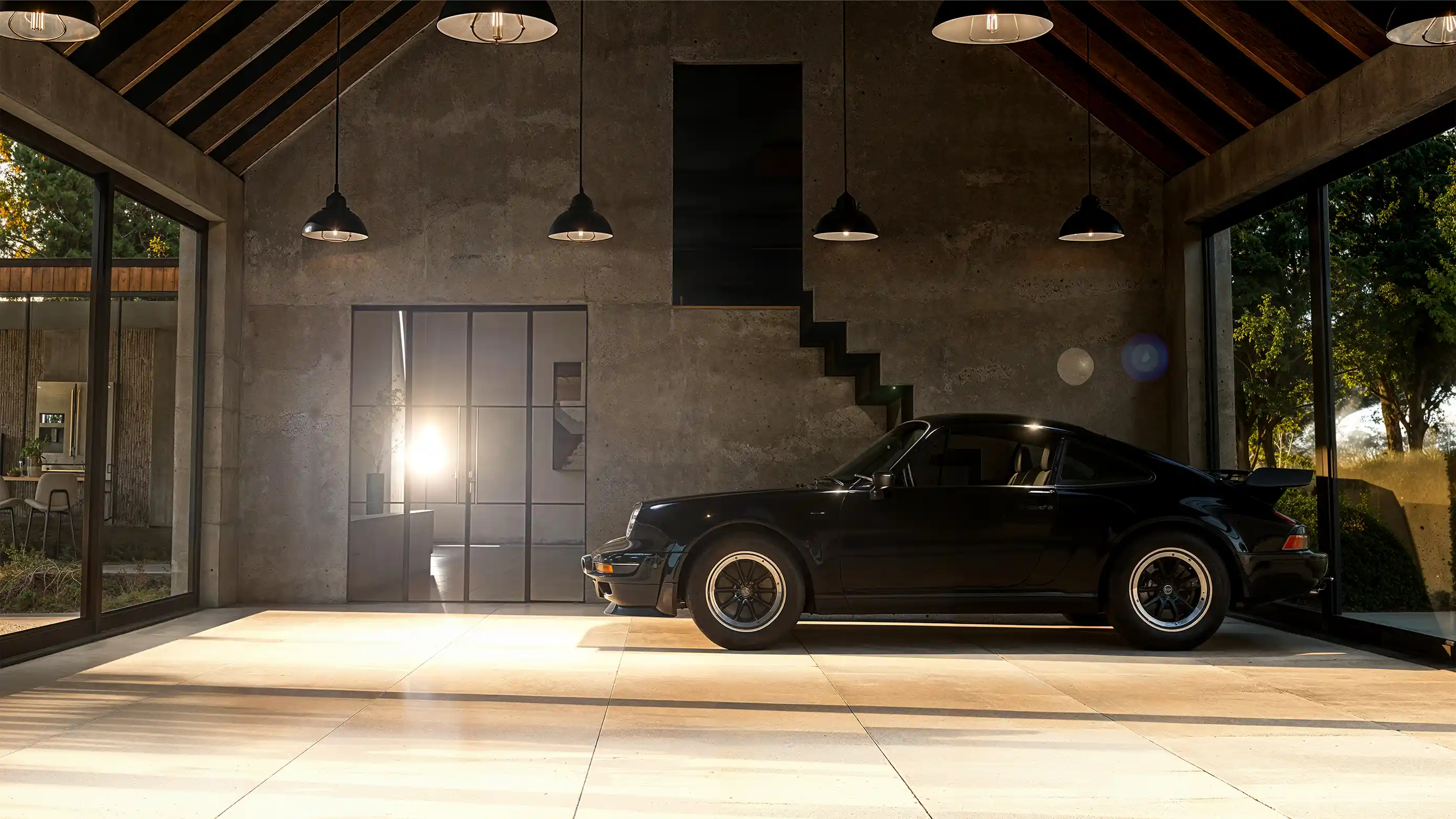 Sort sportsvogn parkeret i moderne garage med betonvægge og store glasvinduer.