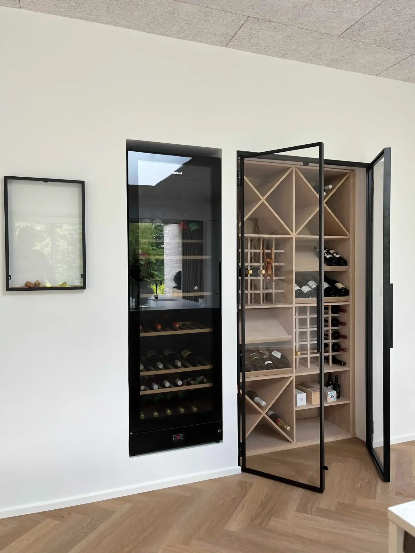 Indbygget vinkøleskab og vinkælder med glasdøre i et moderne rum med lyst trægulv.