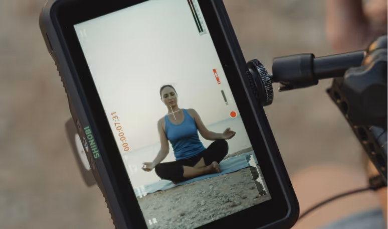 Yoga instructor being filmed on a camera monitor representing creator lifestyle integration and flexible work.
