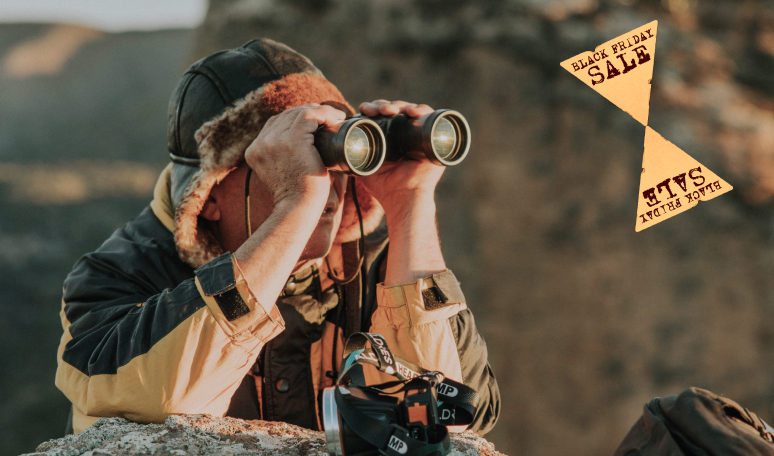 Shopper looking through binoculars at Black Friday sale tags