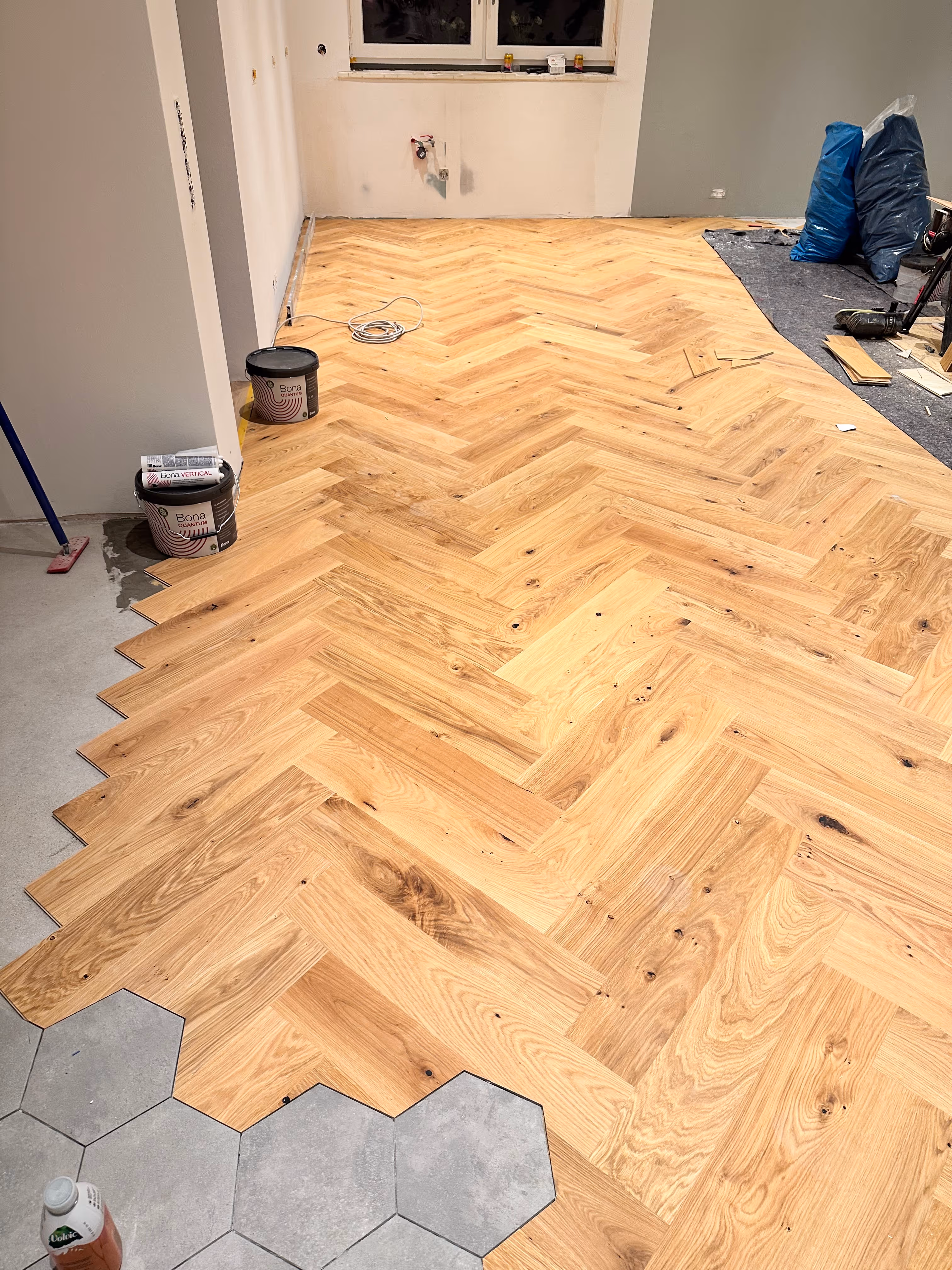 Verlegung von Eichenparkett im klassischen Fischgrät-Muster mit Anschluss an Hexagon-Fliesen in Hennef.