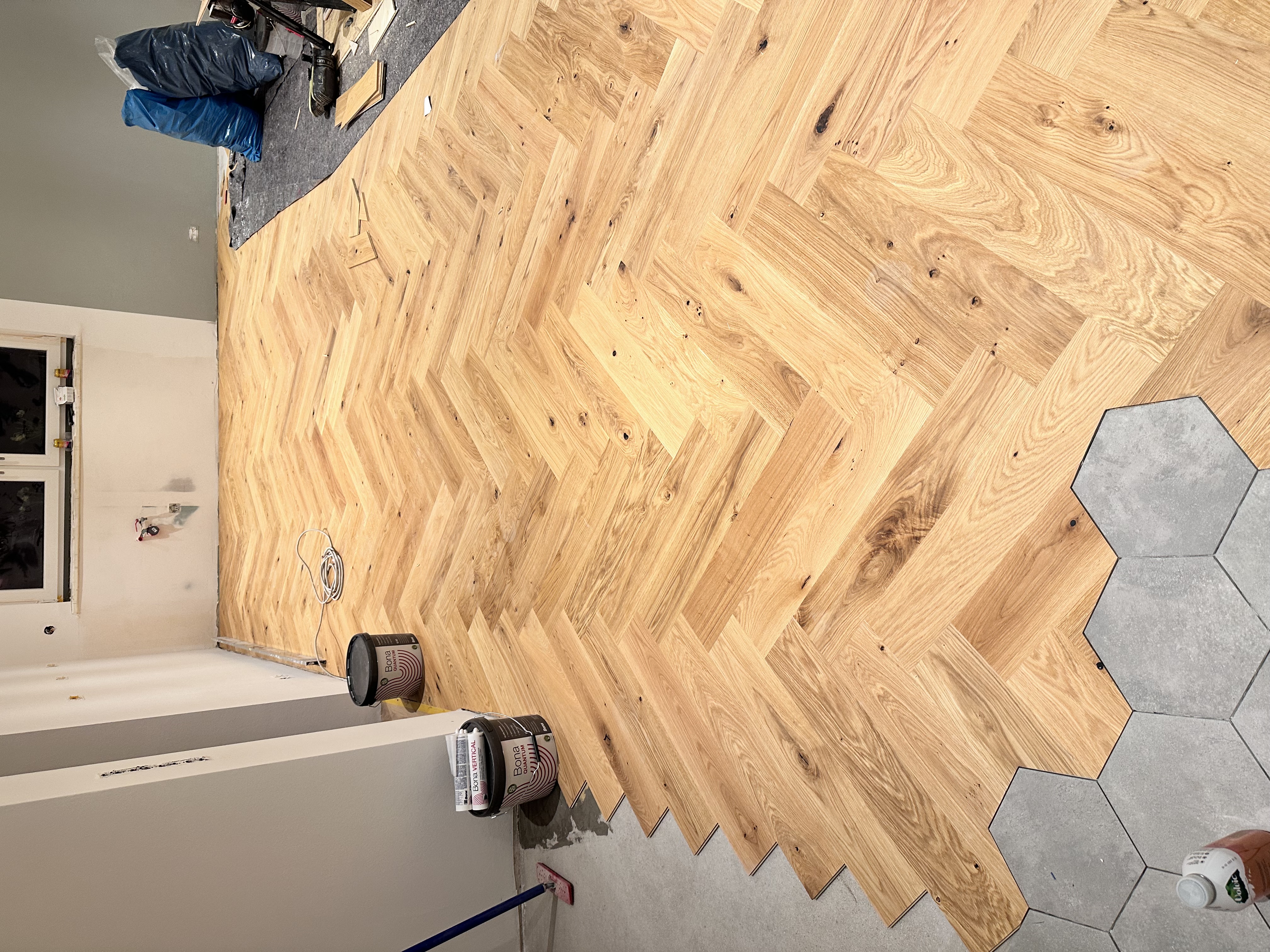 Verlegung von Eichenparkett im klassischen Fischgrät-Muster mit Anschluss an Hexagon-Fliesen in Hennef.