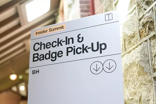Sign indicating Check-In & Badge Pick-Up for Insider Summit with two downward arrows.
