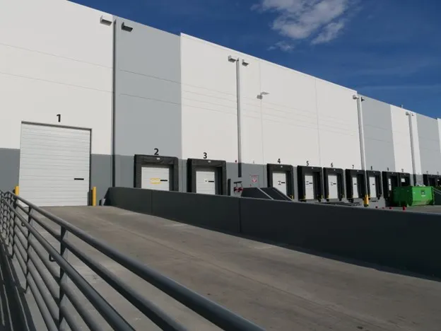 Loading dock with numbered bays 1 to 7 at a large warehouse under a clear blue sky.