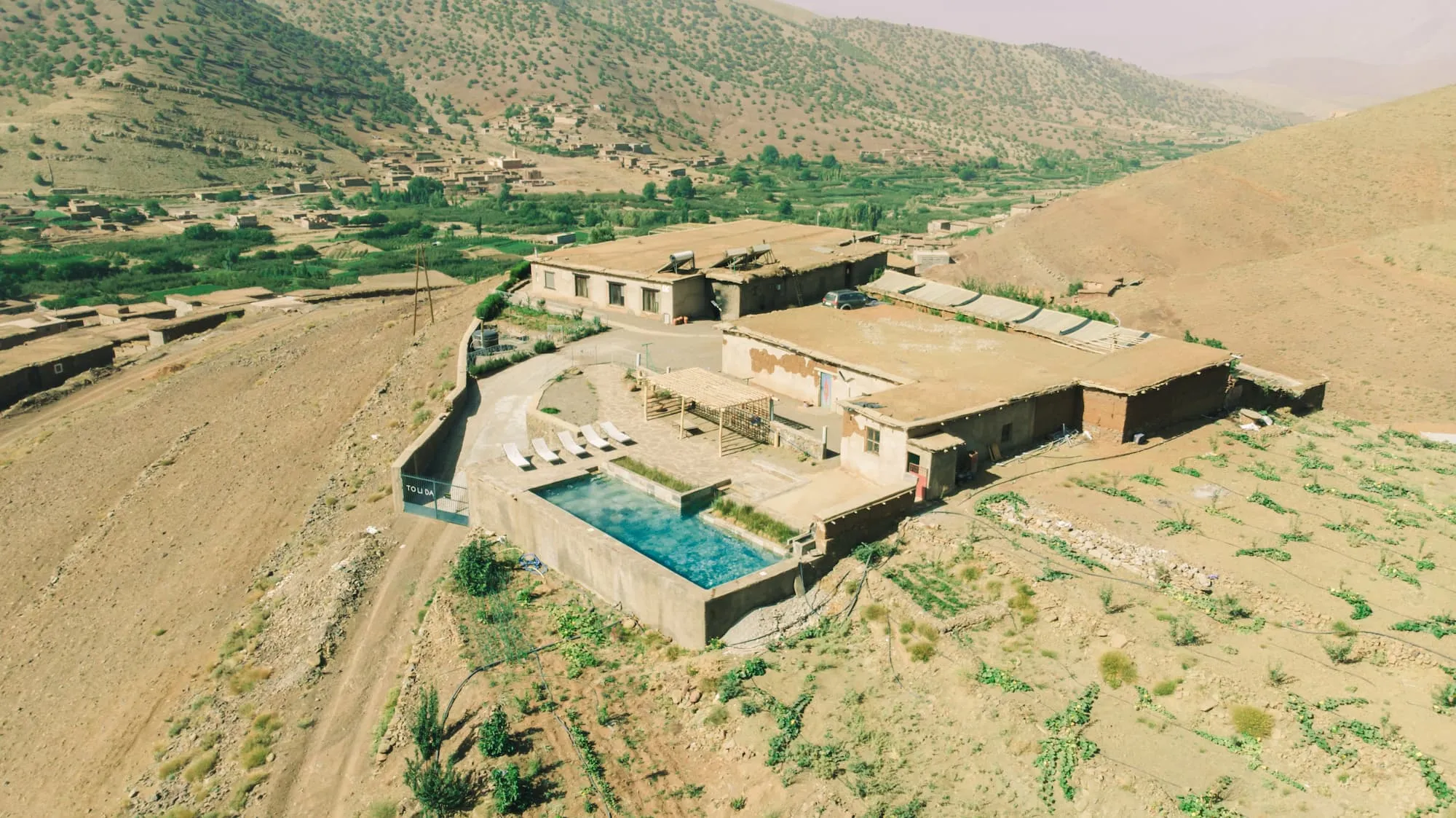 Vue de Touda Ecolodge au Maroc batiment en terre avec piscine surplombant Zawiyat Oulmzi au vallée des Bougmez au Maroc.