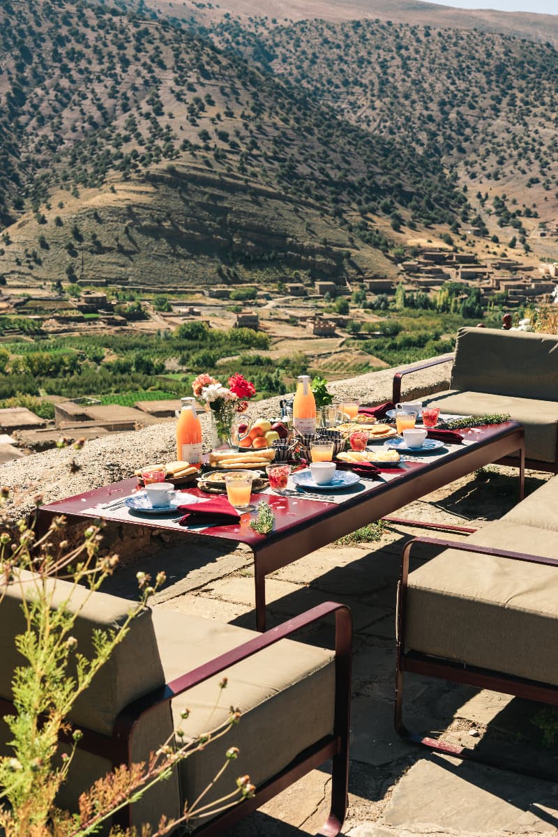 La terrasse de l'écolodge Touda avec table de petit-déjeuner donnant sur la vallée Bougemez dans les montagnes du Haut Atlas.