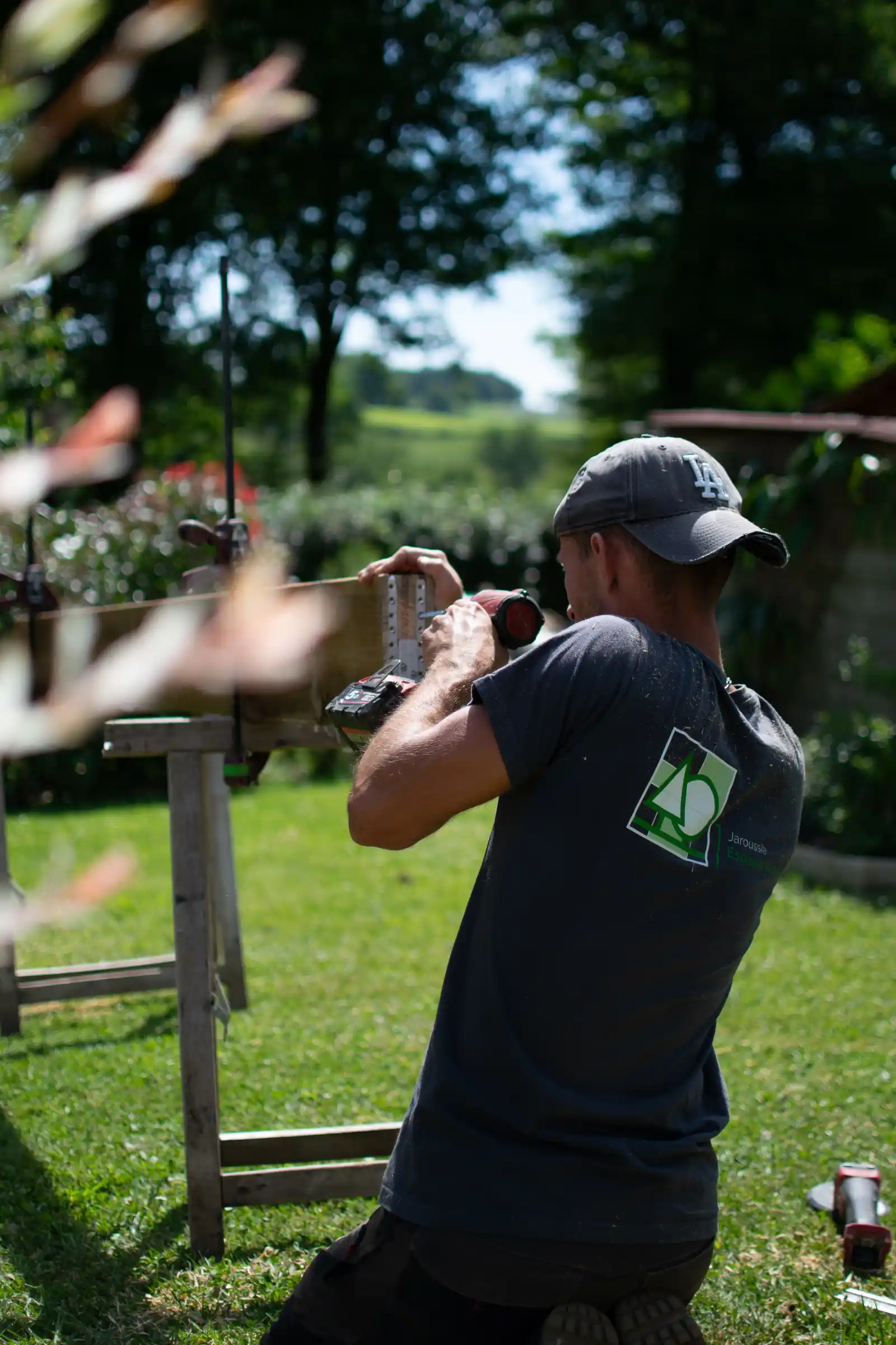 Paysagiste maçon qui perce une planche de bois pour une terrasse de Dordogne