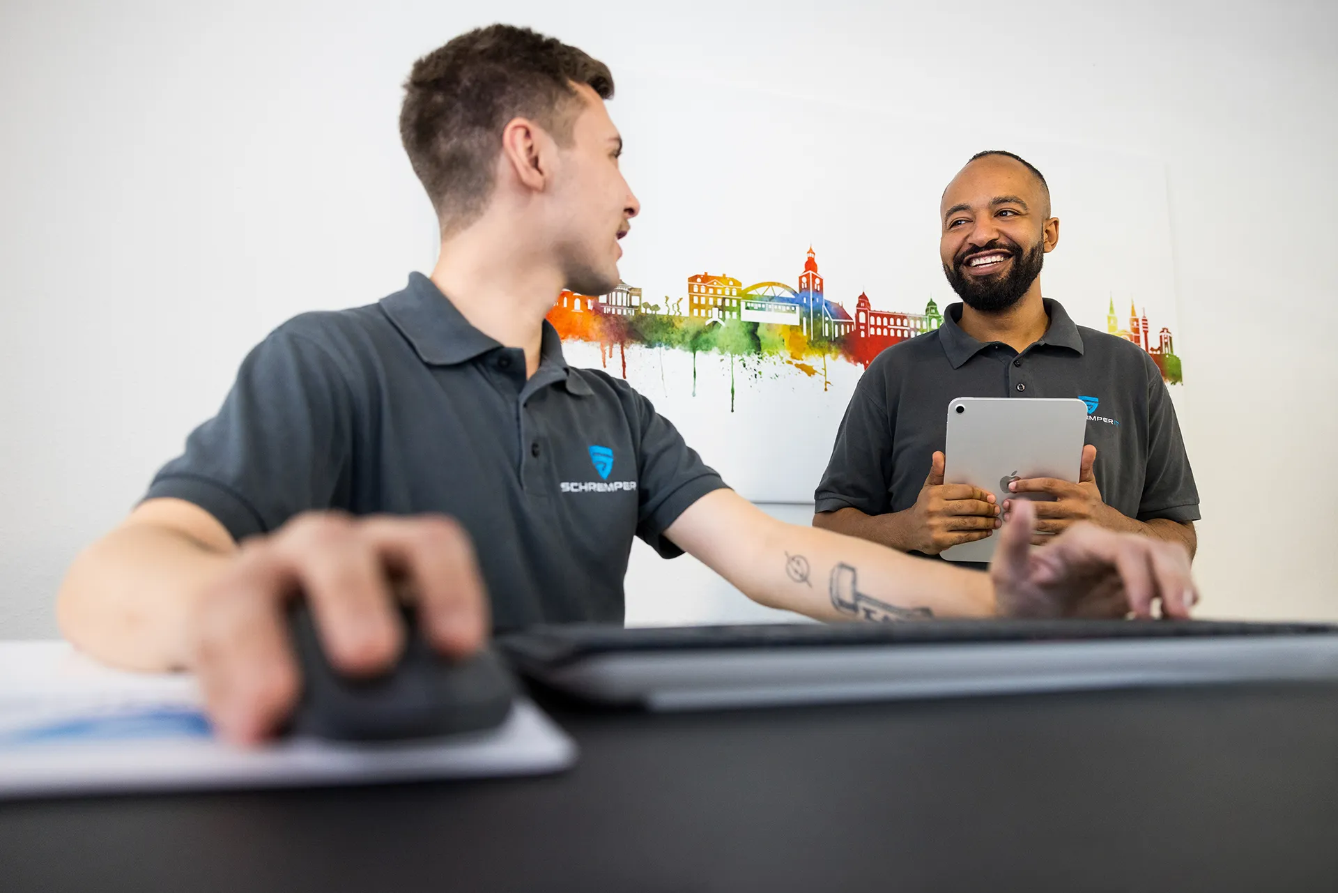 Zwei Mitarbeiter der Schremper IT GmbH besprechen sich am Schreibtisch in den Geschäftsräumen in Wuppertal.