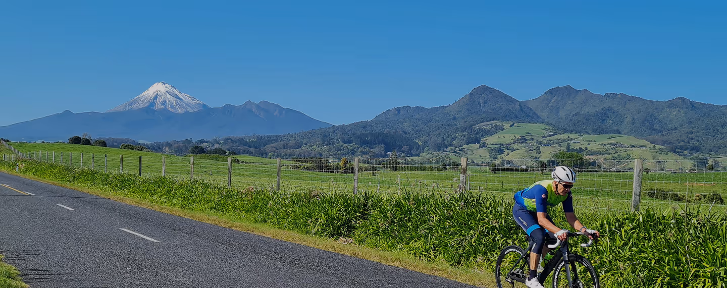 Radfahrer auf Landstraße mit Bergkulisse – Symbol für Freiheit und Naturverbundenheit.