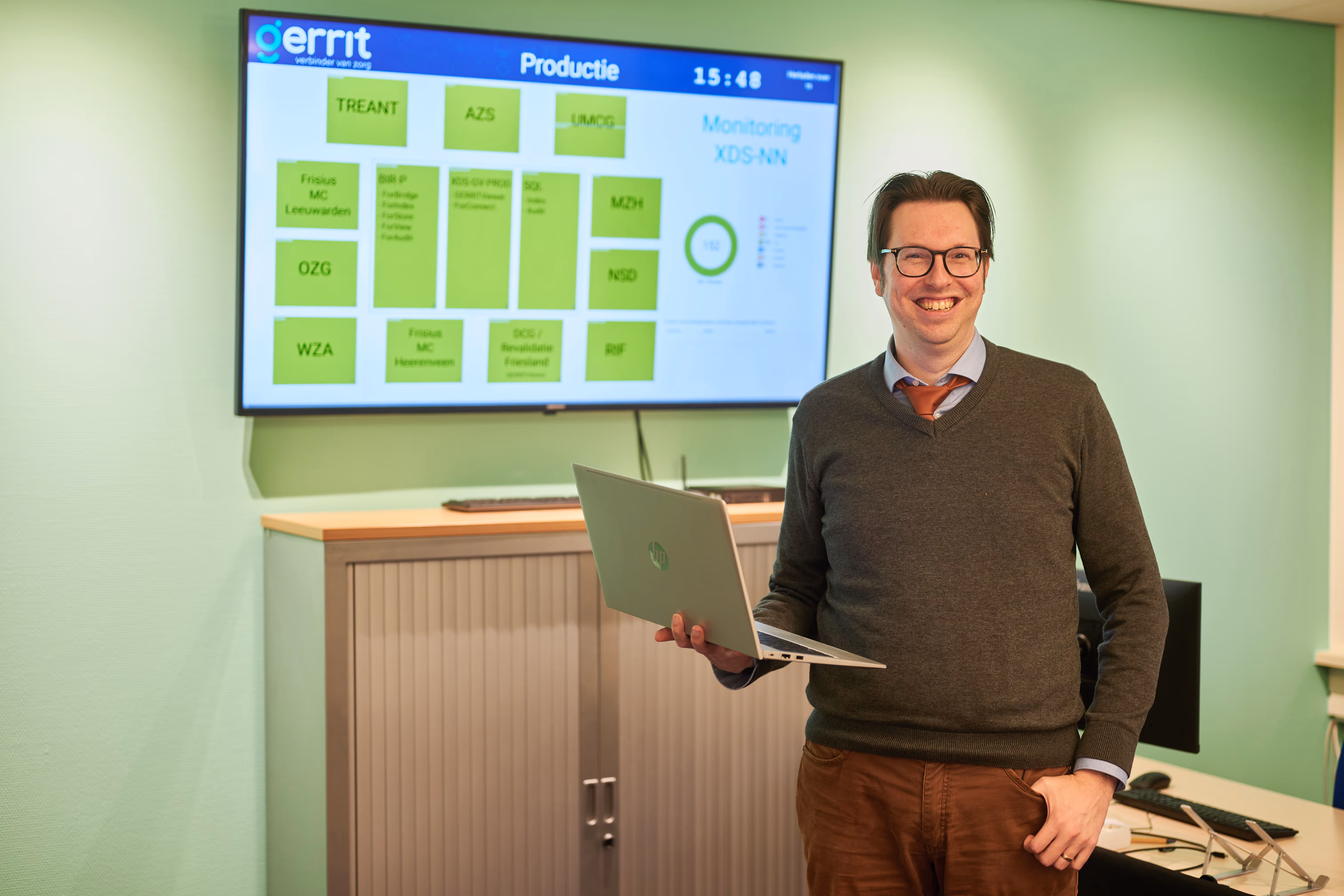 Medewerker staat glimlachend bij scherm