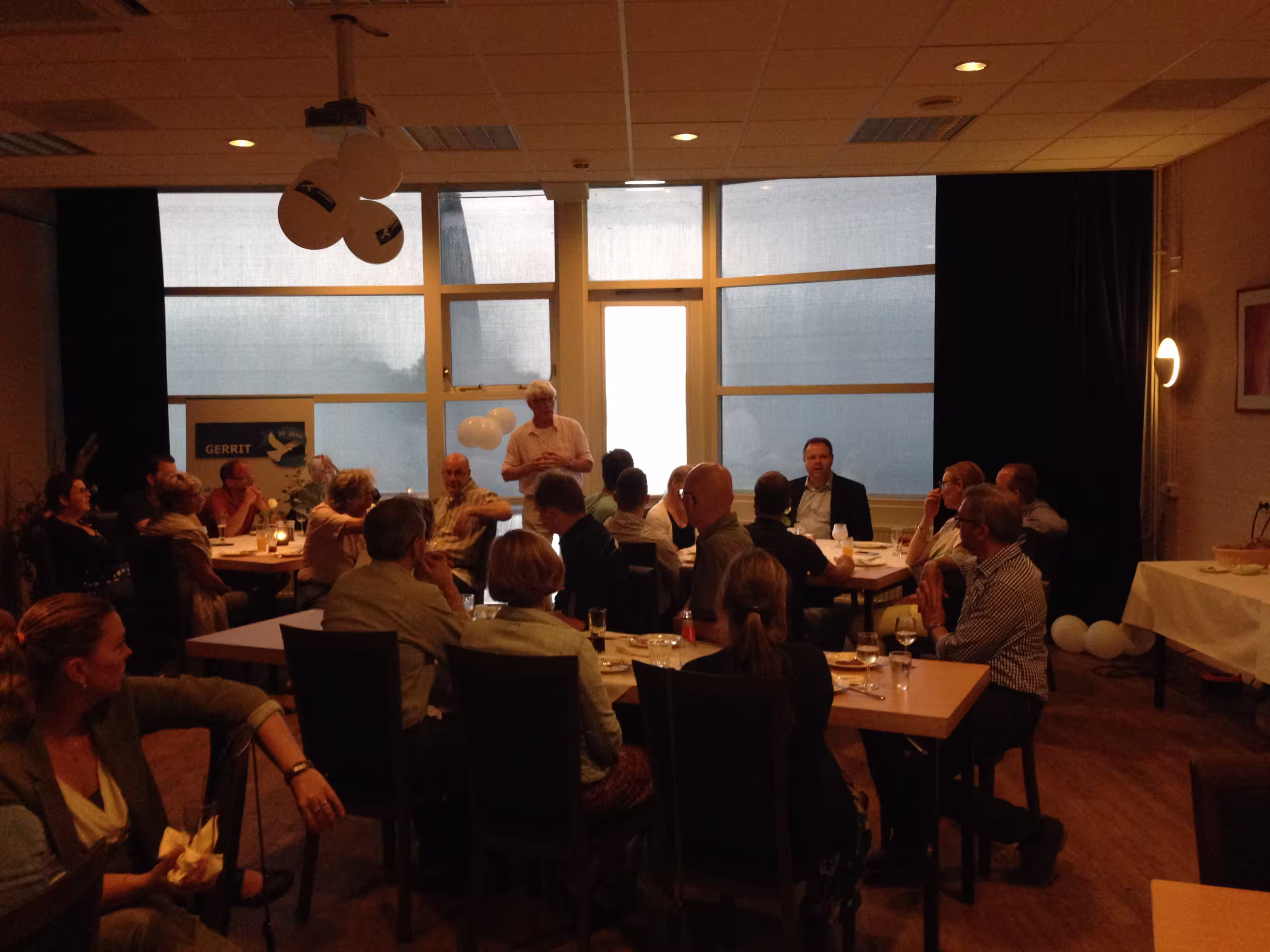 Stuk of 20 mensen in een vierkant aan tafel in overleg