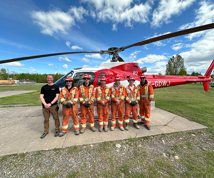 HyTech Drilling team stands in front od helicopter