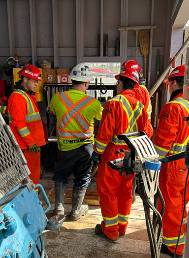 HyTech Drilling team members gathered around a screen on the drill site.
