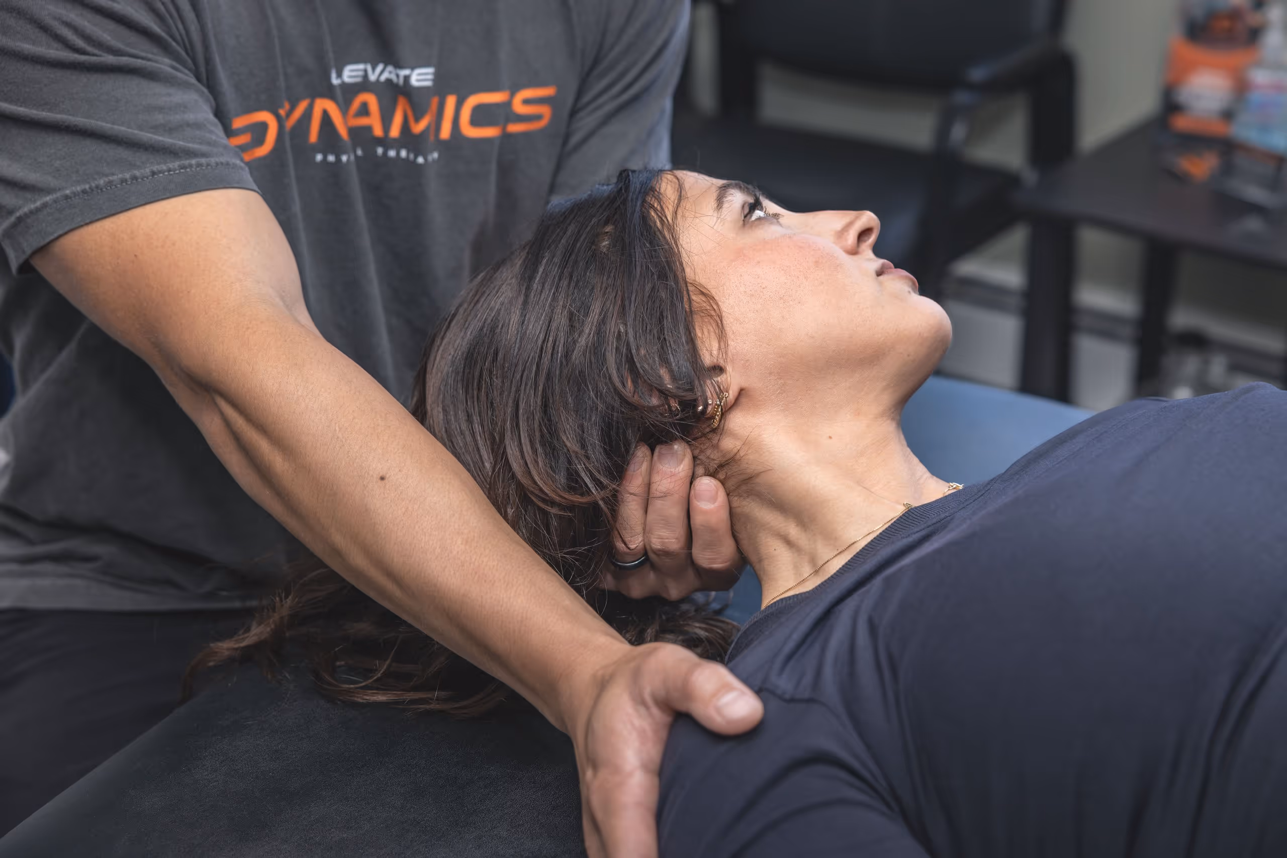 Therapist performing neck adjustment on a woman lying on a treatment table. massapequa physical therapy