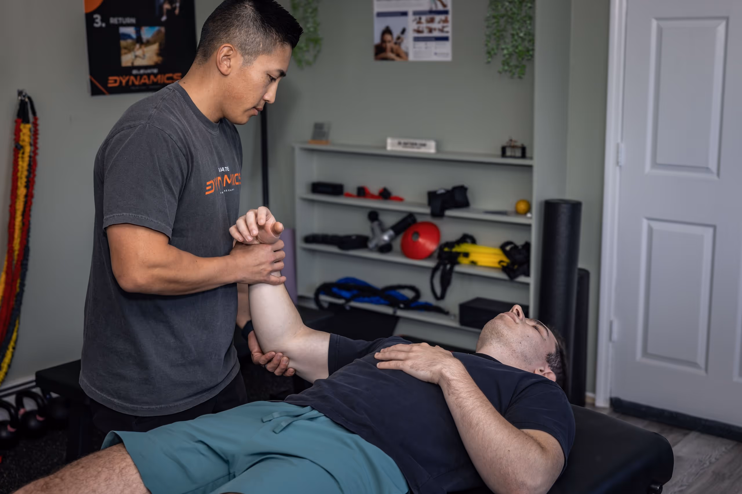 Physical therapist stretches the arm of a man lying on a treatment table in a therapy room. massapequa physical therapy