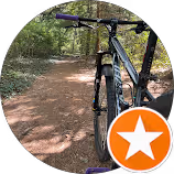 Close-up of a black bicycle handlebar on a dirt trail surrounded by trees. physical therapy massapequa ny