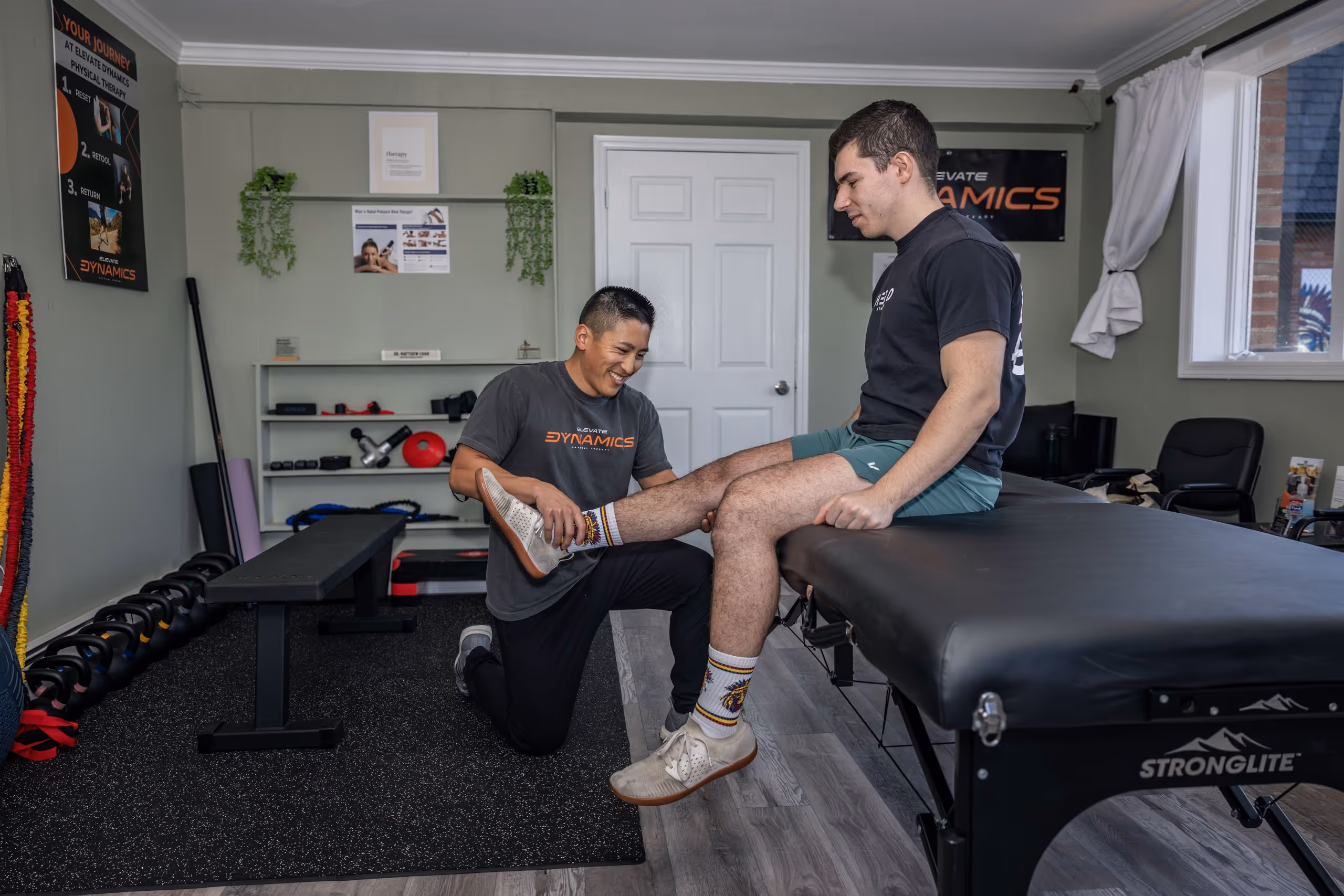 Elevate Physical therapist kneeling while examining a patient's lower leg in a therapy room. physical therapy massapequa ny