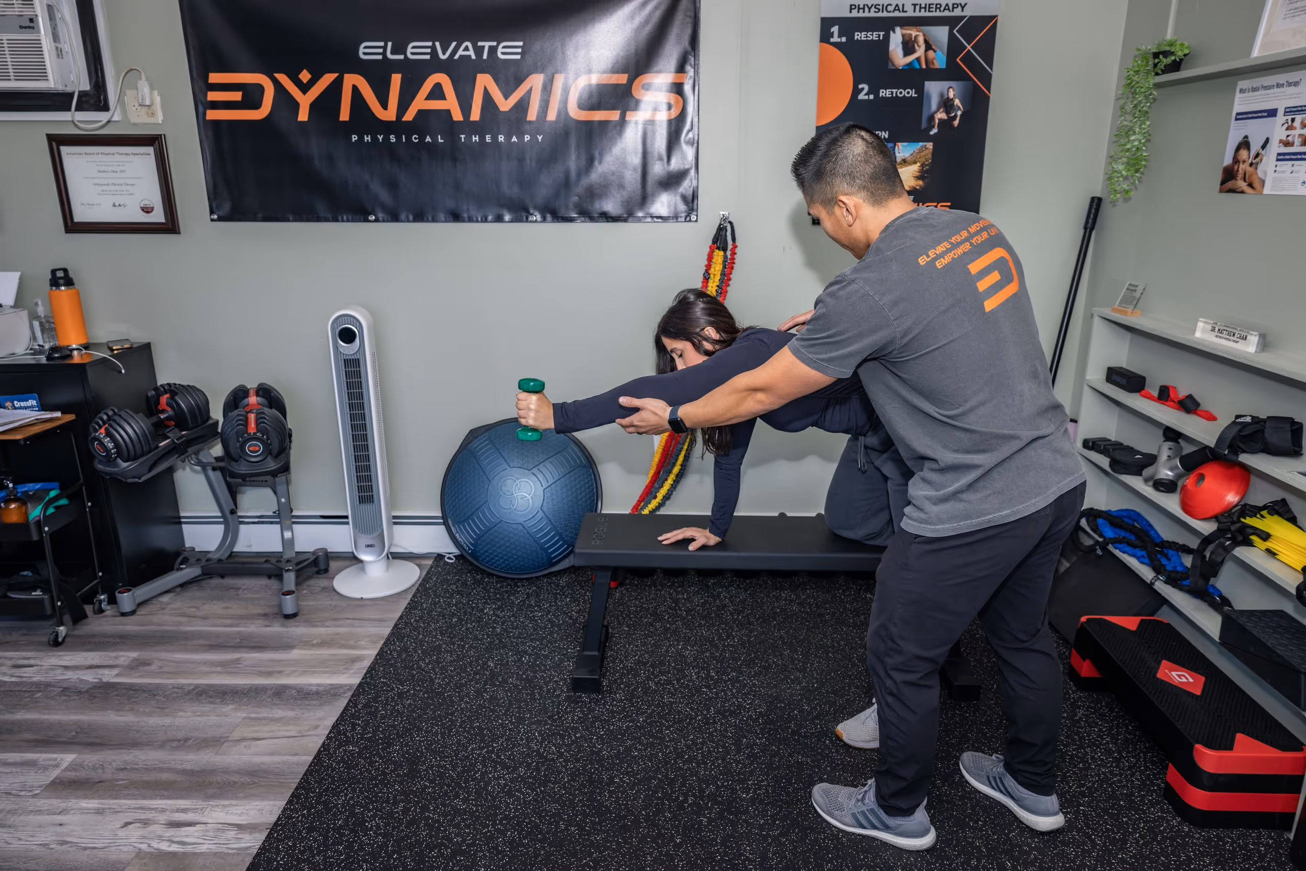 Elevate Physical therapist assisting a woman performing a dumbbell exercise on a bench in a therapy gym. physical therapy massapequa ny