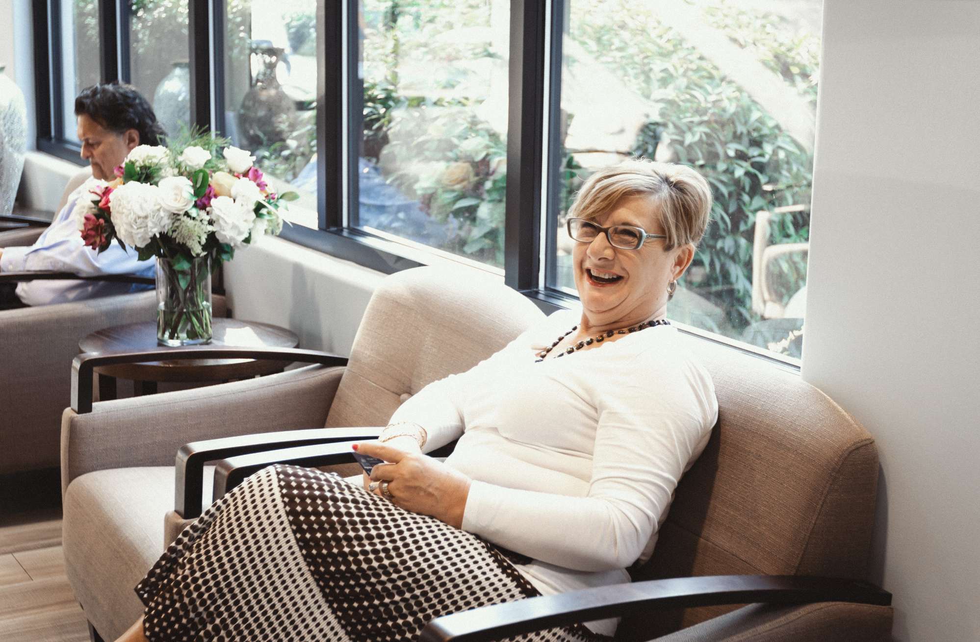 A smiling female patient sits on a sofa in our lobby