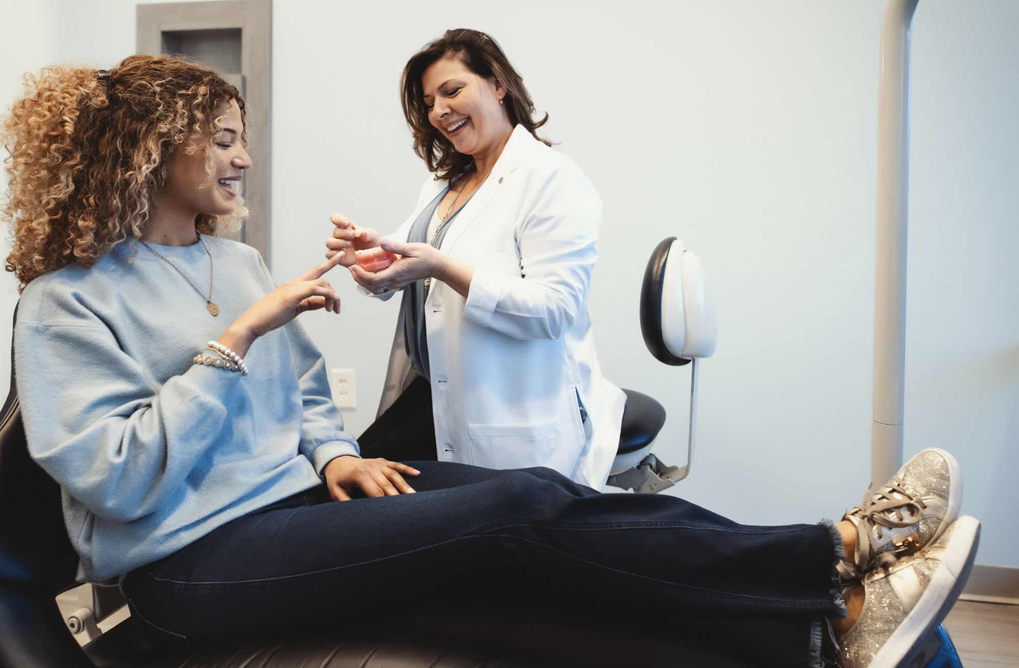 A dentist shows a patient a dental model