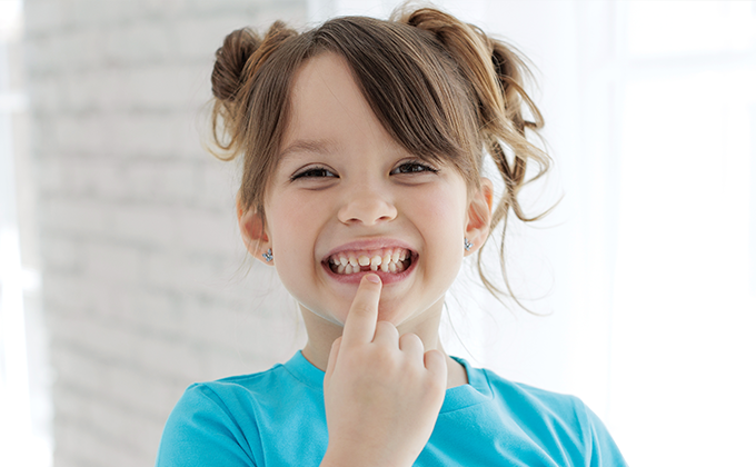 Child with a loose baby tooth and growing permanent teeth, highlighting pediatric dentistry, children's dental care, tooth development, oral health education, preventive dental care, family dentistry, and healthy smile growth