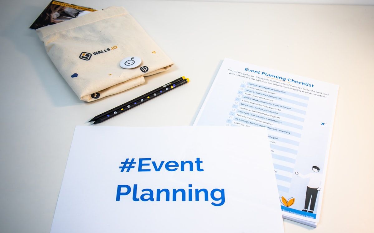 A printed onboarding roadmap laid out on a desk beside a calendar marked into the first 90 days, with a checklist of licensing steps, appointment-setting milestones, and case submission tasks, plus a folder of welcome materials and a pair of headsets ready for call practice