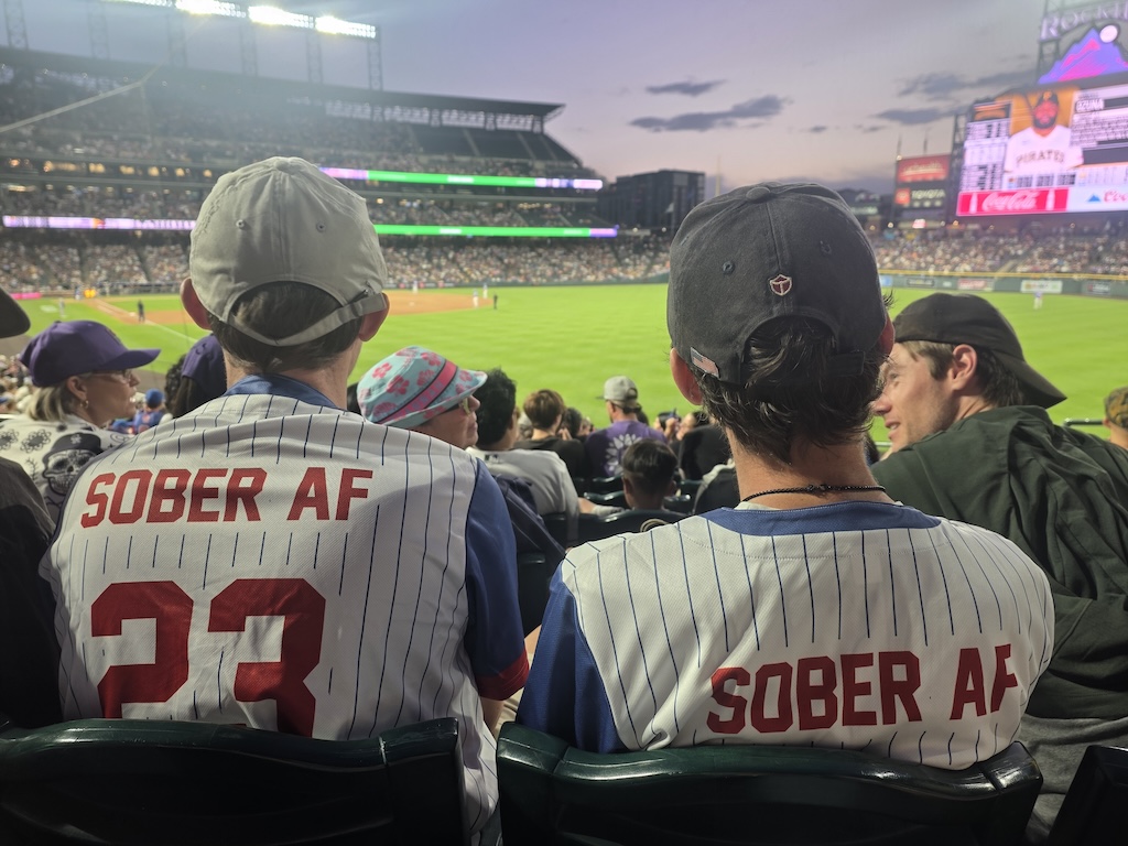 Two attendees at a Colorado Rockies game wearing Sober AF number 23 jerseys.