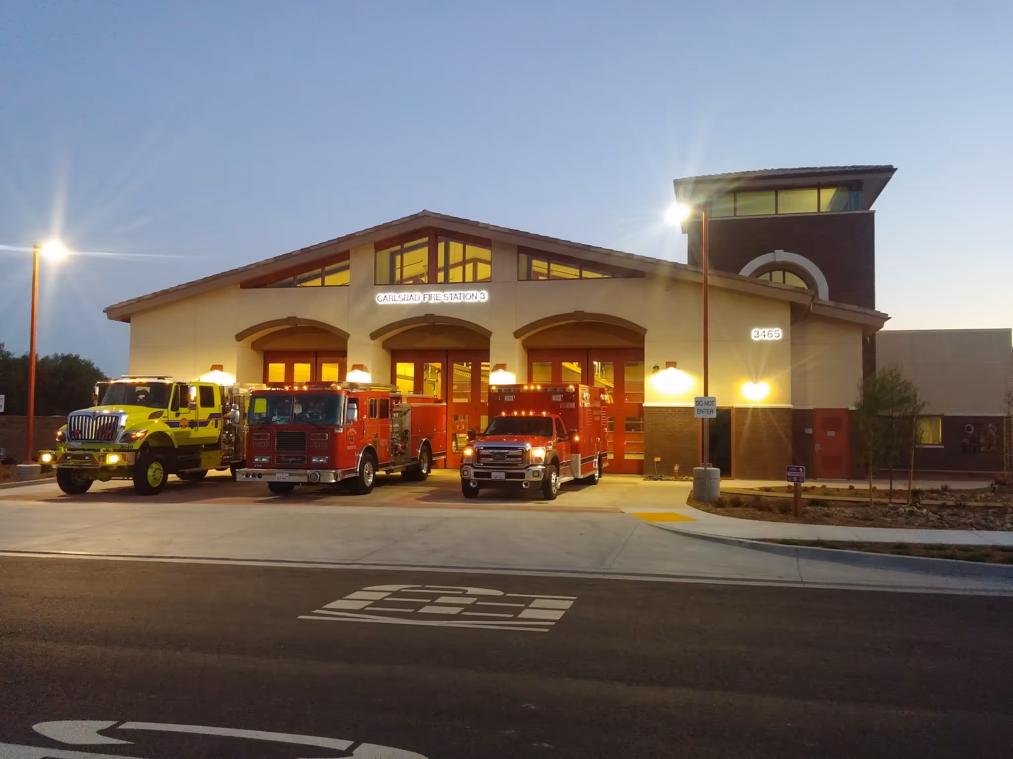 Carlsbad Fire Station 3 building at dusk with three emergency vehicles parked in front.