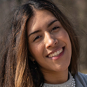 Smiling young woman with long brown hair and natural makeup wearing a gray top.