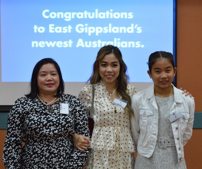 Three women standing in front of a sign that says 'Congratulations to East Gippsland's newest Australians.'