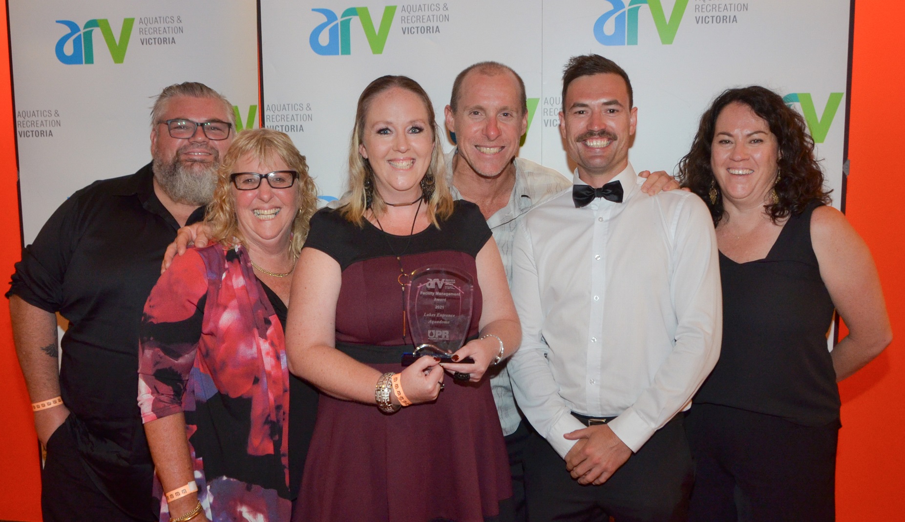 Group of people smiling and holding an award.