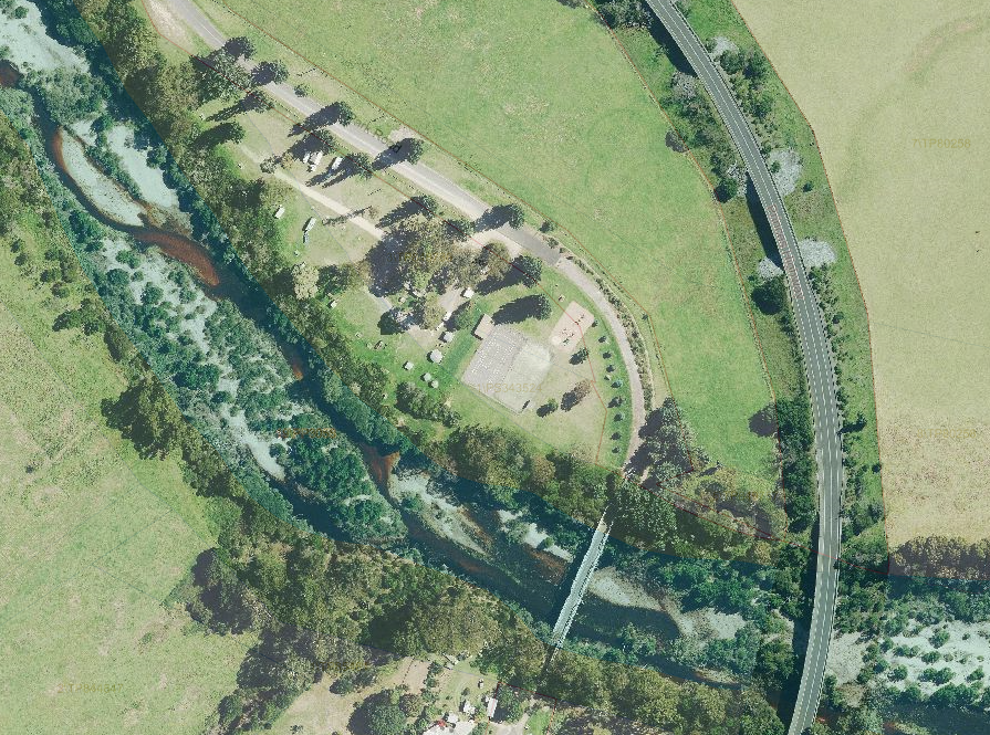 Aerial photo of tennis courts next to a river in a rural setting.