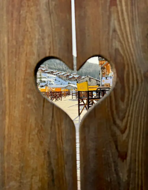 Terrace of the 'Restaurant La Bergerie' with yellow chairs facing a snowy mountain landscape.