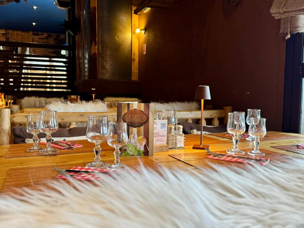 Nordic-themed restaurant interior with a pole structure, an antler chandelier, and tables set with white fur.