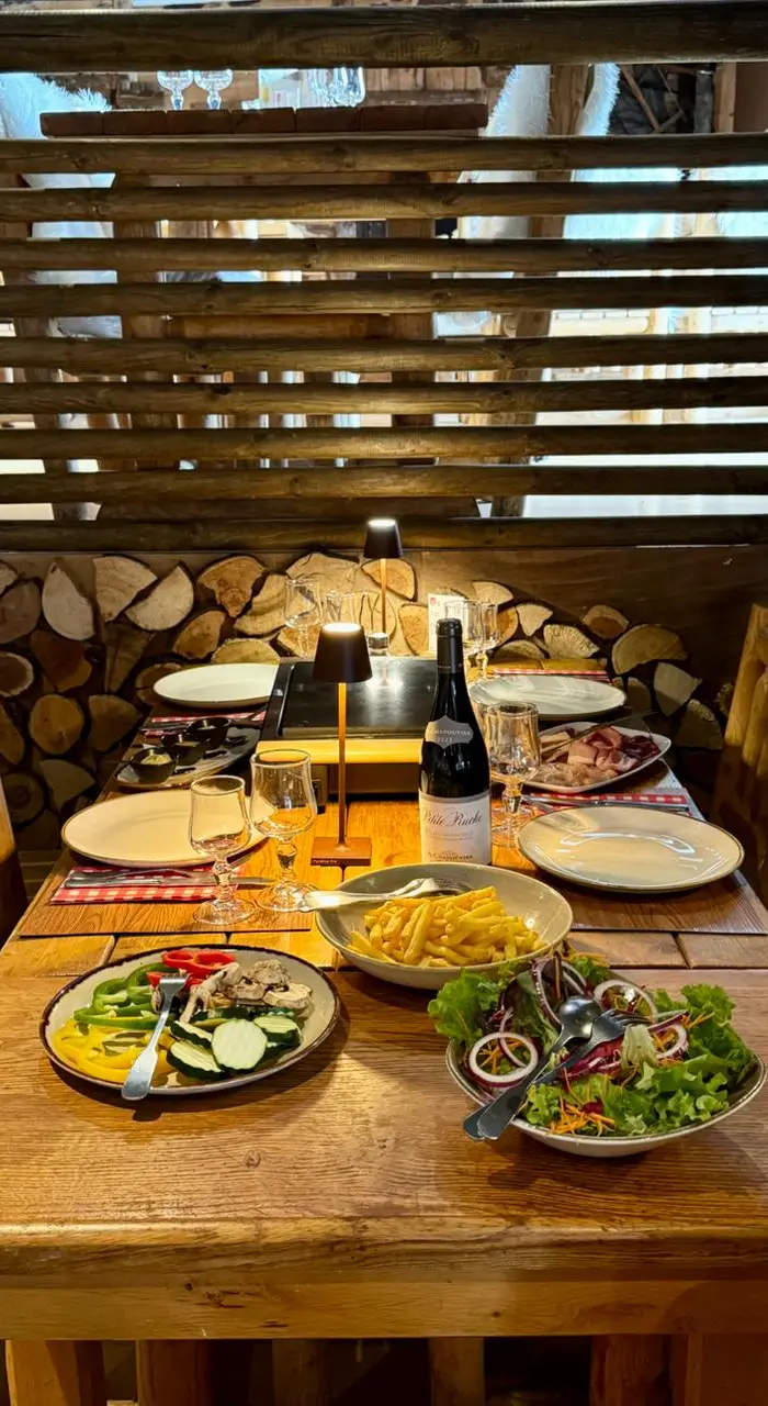 Interior of the restaurant 'Le K2', with a mountain or Nordic lodge theme, featuring wooden furniture, white furs, and a antler chandelier.