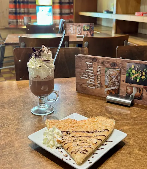 Two cocktails: an Espresso Martini in a stemmed glass and a dark drink over ice in a hammered copper mug, on a wooden table.