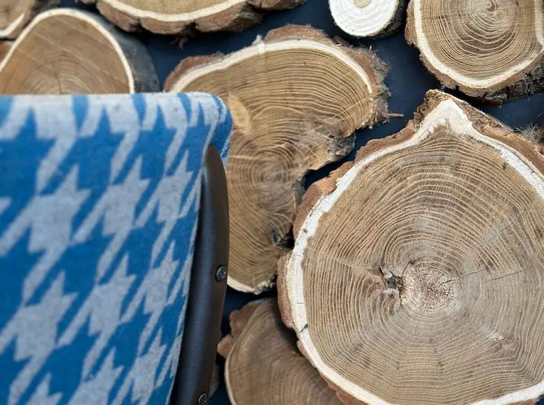 Vue intérieure d'un espace du restaurant VÔGA GOGA au décor de montagne moderne, avec des tables en bois, des chaises à motifs bleus et blancs, un bar avec un comptoir en bois brut, et un plafond décoré de panneaux texturés rappelant la fourrure