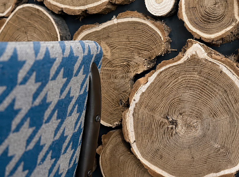 Vue intérieure d'un espace du restaurant VÔGA GOGA au décor de montagne moderne, avec des tables en bois, des chaises à motifs bleus et blancs, un bar avec un comptoir en bois brut, et un plafond décoré de panneaux texturés rappelant la fourrure